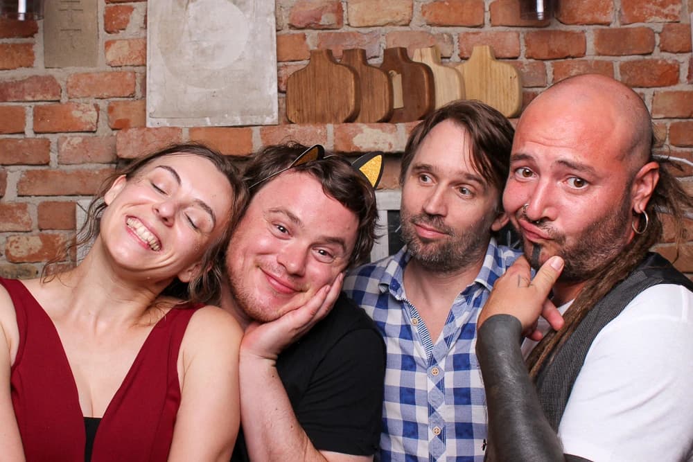 Eine Gruppe von vier Personen lächelt mit Fotobox-Accessoires