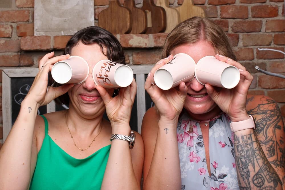 Zwei Frauen posieren in der Fotobox mit Pappbechern als Ferngläser